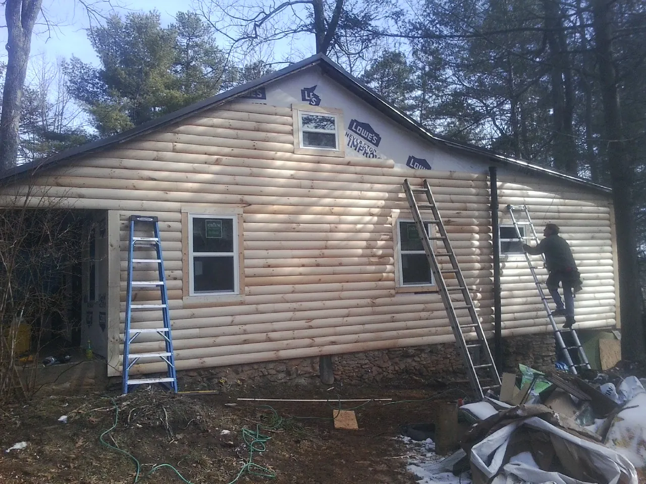 Ladders set against fresh log siding during an exterior remodel in Chelsea
