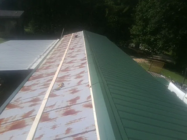 Old rusted panels beside newly installed green metal roofing — Wind Damage Roof Repair by Roofing Brothers in Chelsea