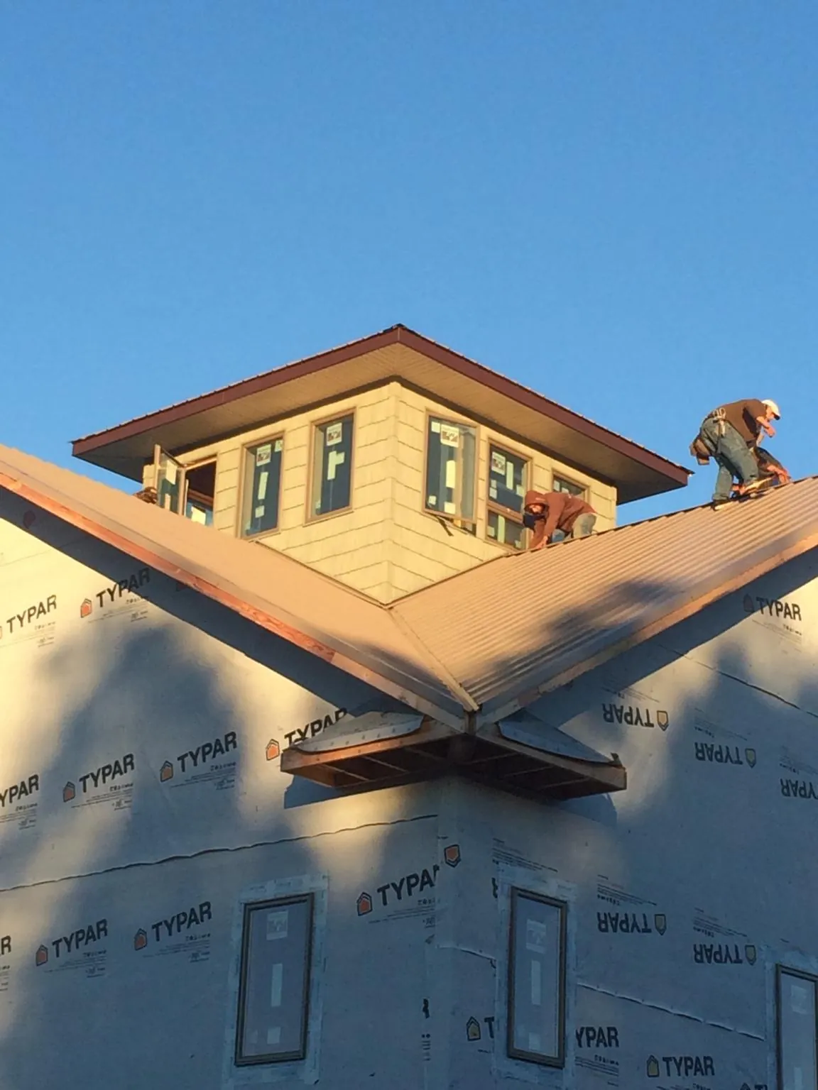 Roofers working around a rooftop cupola on a new metal roof at sunset — Roof Waterproofing in Chelsea by Roofing Brothers